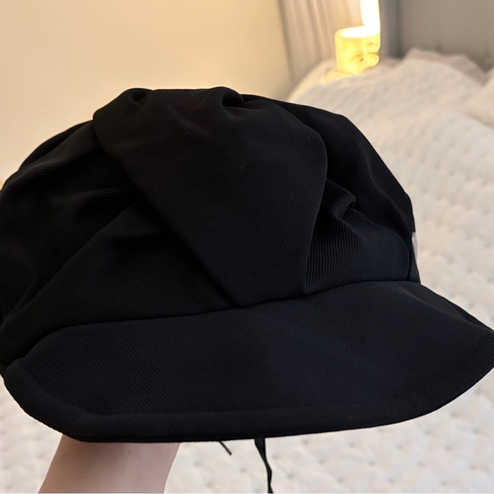 Black newsboy hat with adjustable strap.